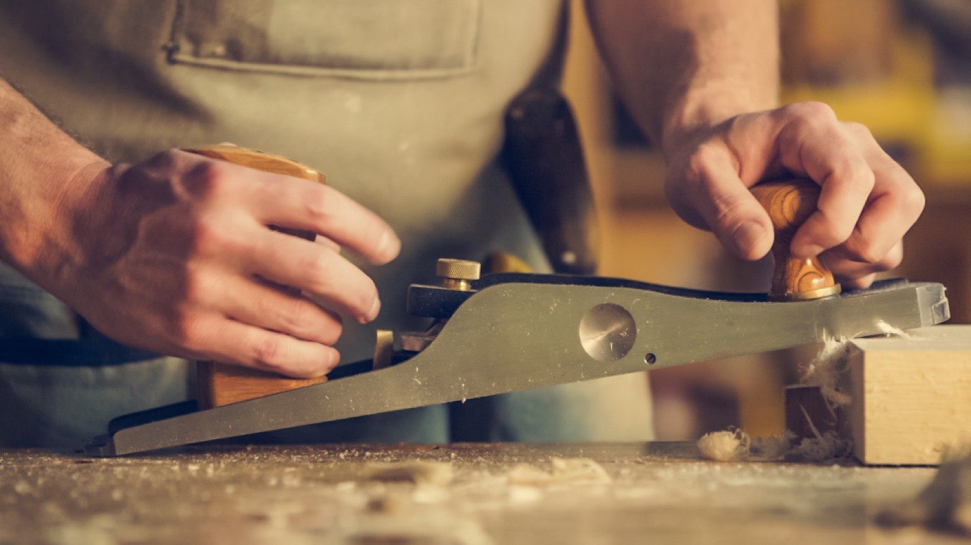 A carpenter smoothing a board with a hand plane